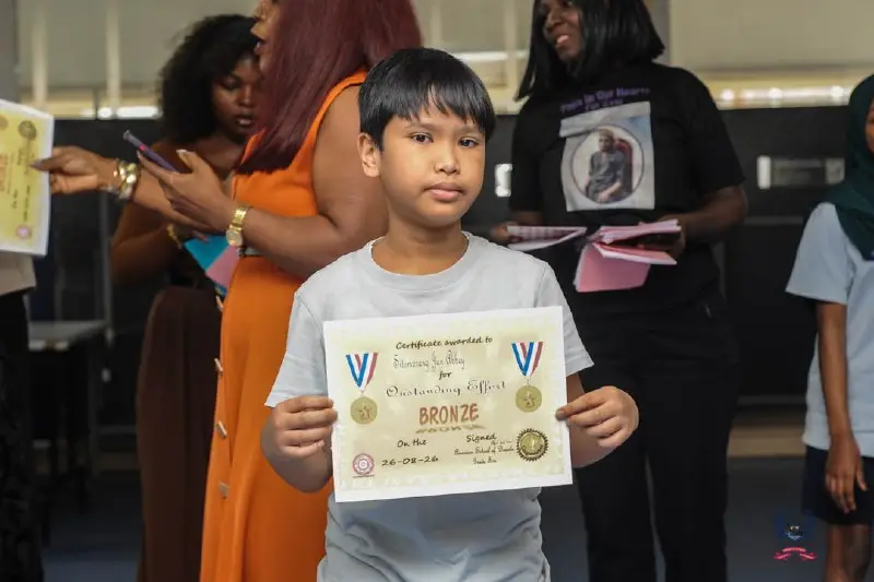Young student celebrates an October Student of the Month achievement alongside adults at American School of Douala.
