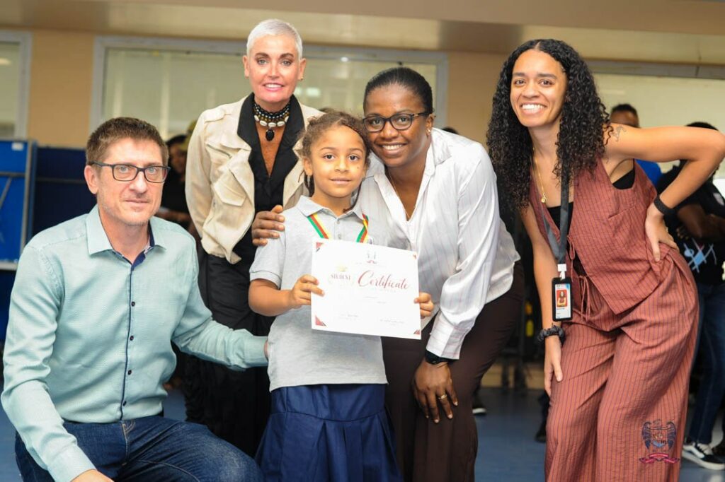 American School of Douala student proudly displays a Student of the Month certificate alongside members of the school community.