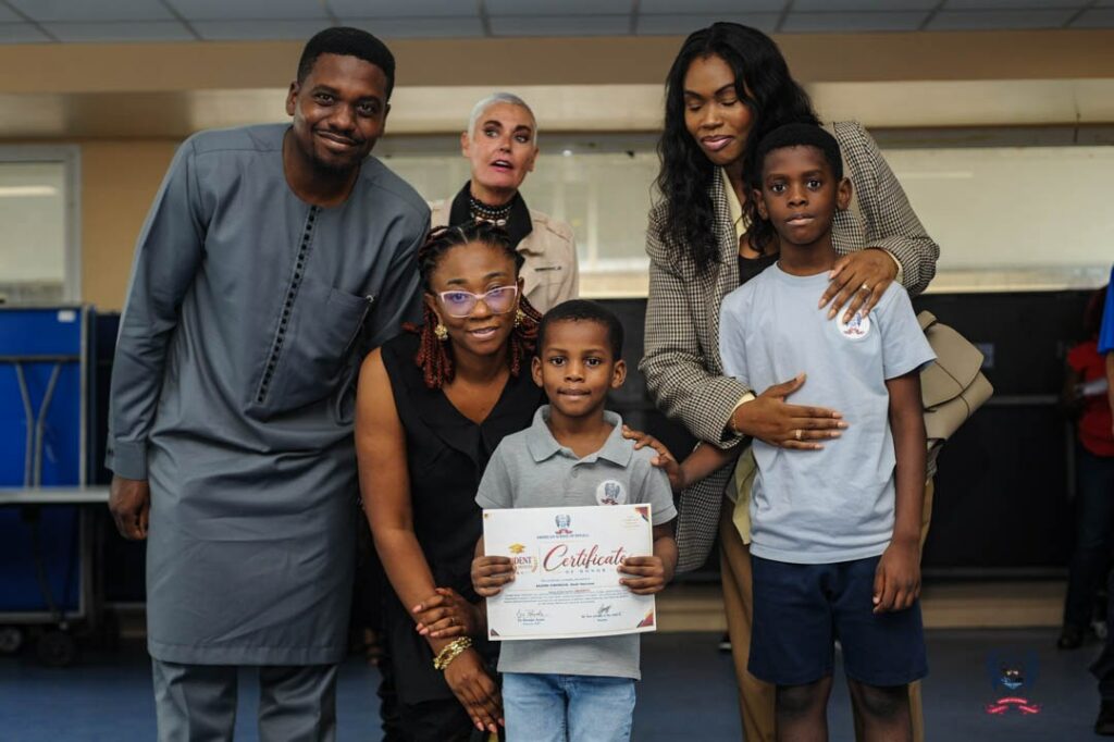 Two young American School of Douala students display certificates alongside adults during the October Student of the Month awards.